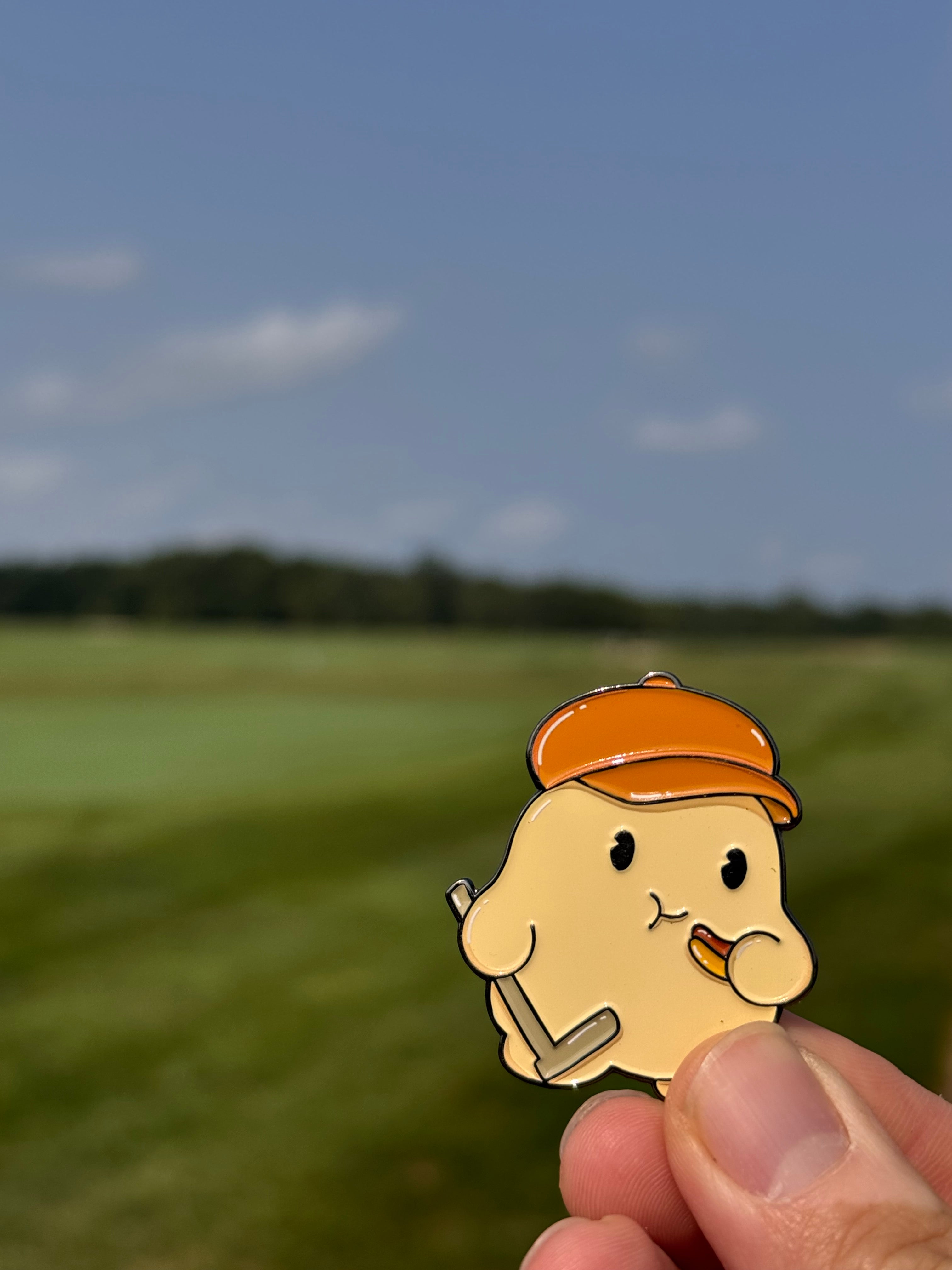 Cartoon bear character with a hat and tool held by a hand against a blurred natural background